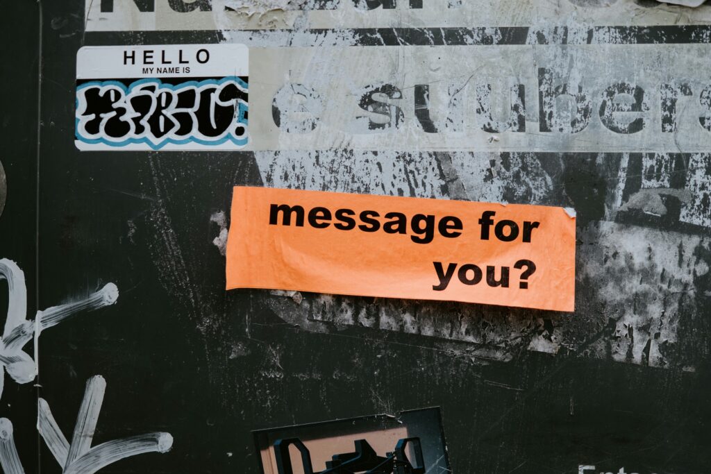 Orange sticker reading "message for you?" on a textured wall, reflecting key questions producers should ask in audio post.