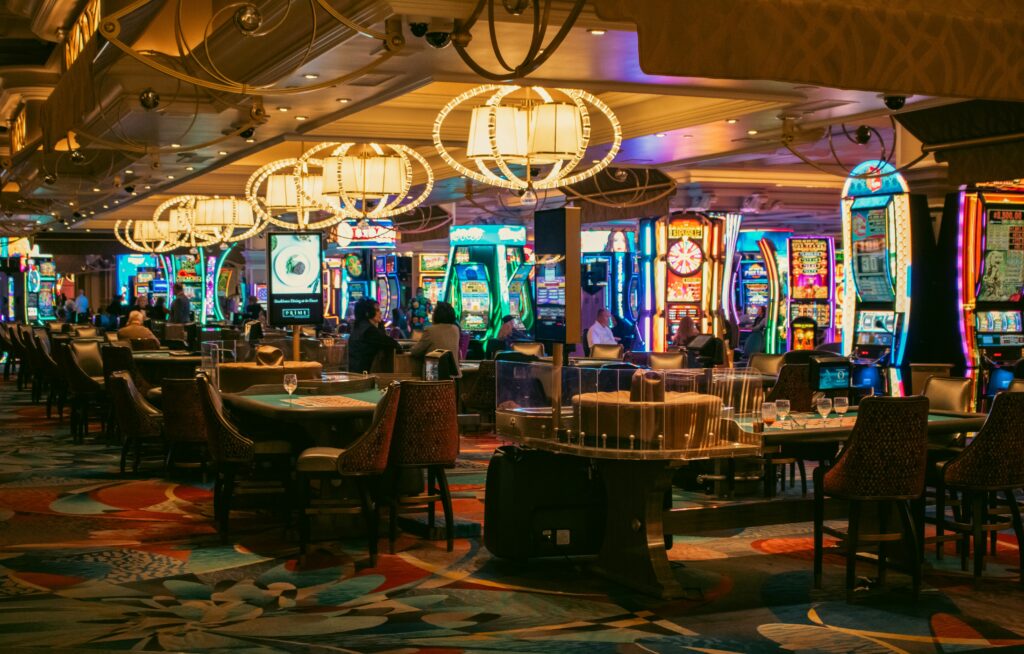 The opulent casino floor of the Bellagio Hotel in Las Vegas, featuring rows of gaming tables, ornate chandeliers, and flashing slot machines. The carefully managed soundscapes and luxurious environment are designed to encourage players to relax and gamble longer